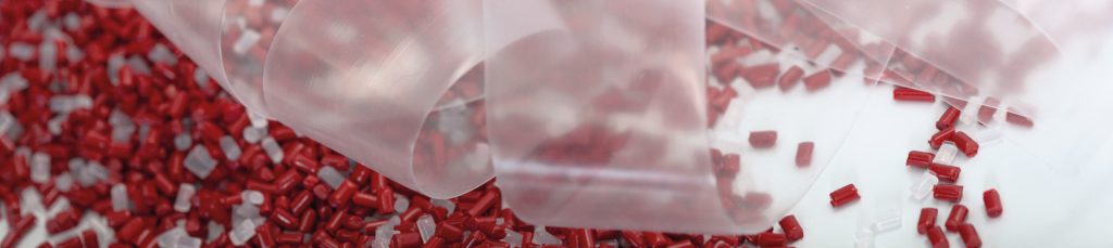 small red and transparent particles of plastics/rubber with transparent ribbon over them